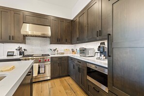A modern kitchen with dark wood cabinets, stainless steel appliances, and a marble countertop.