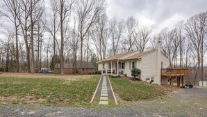 A single-story house with a front porch, a gravel driveway, and a wooden deck.