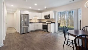 A modern kitchen with white cabinets, stainless steel appliances, and a dining area with a table and chairs.