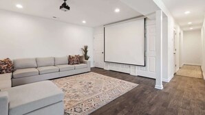 A modern living room with a sectional sofa, a large rug, and a white entertainment unit.