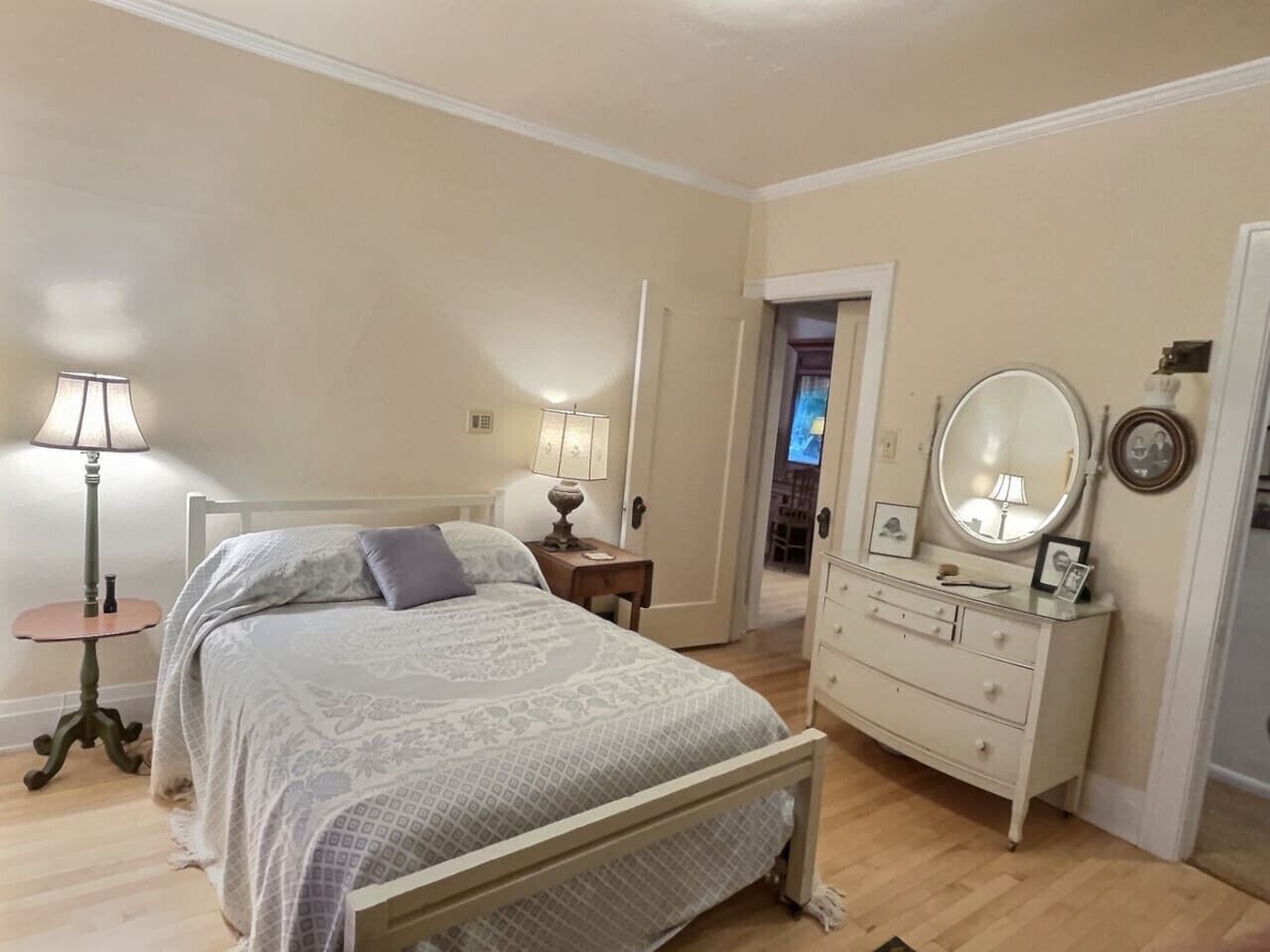 A bedroom with a bed, bedside tables, a dresser, and a mirror.