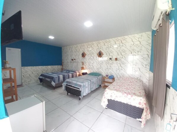 A room with two beds, a desk, a chair, a TV, and a window with curtains.