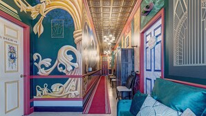 A hallway with a red carpet, ornate wall decorations, and a teal sofa with patterned cushions. - Sleep Up to 22 on a 62 acre "island" in 2 Guest Houses! (Clermont)