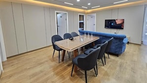 A modern dining area with a wooden table and chairs, a blue sofa, and recessed ceiling lighting. - Central Guest house (Ulaanbaatar)