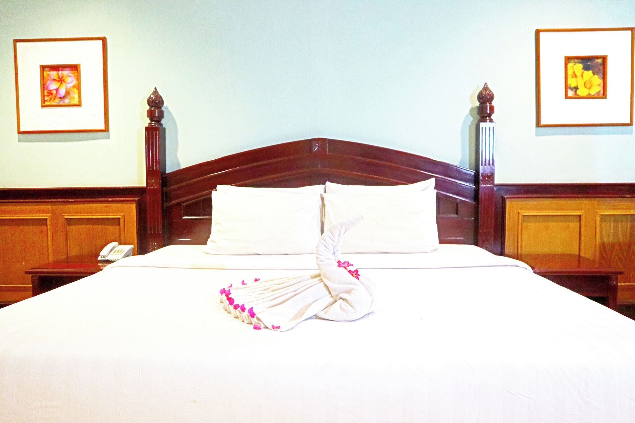 A neatly made bed with white linens and a decorative towel arrangement.