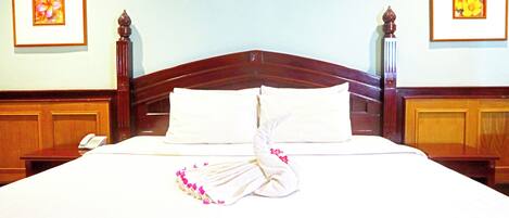 A neatly made bed with white linens and a decorative towel arrangement.