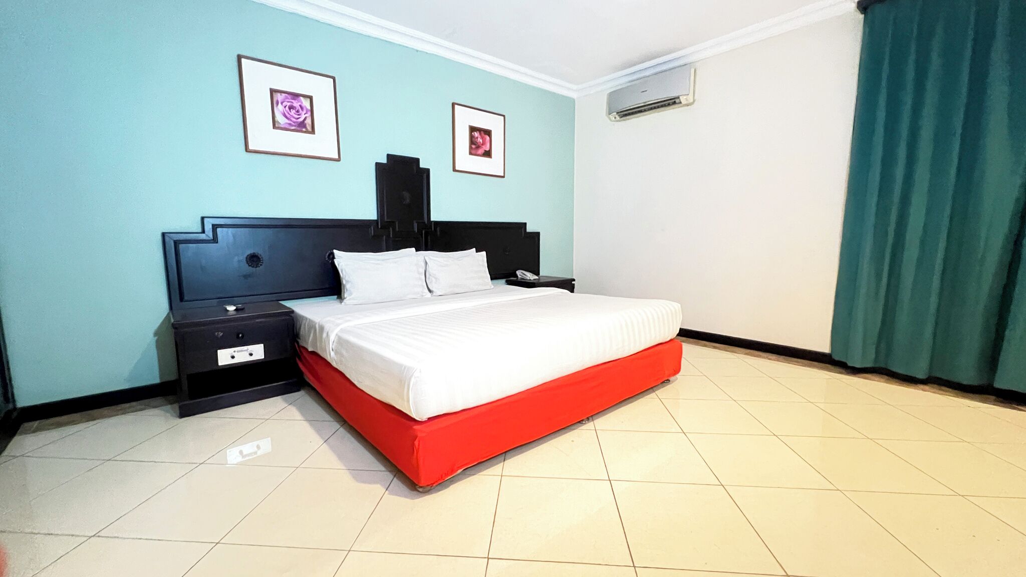 Un dormitorio con cama, mesita de noche y dos cuadros enmarcados en la pared.