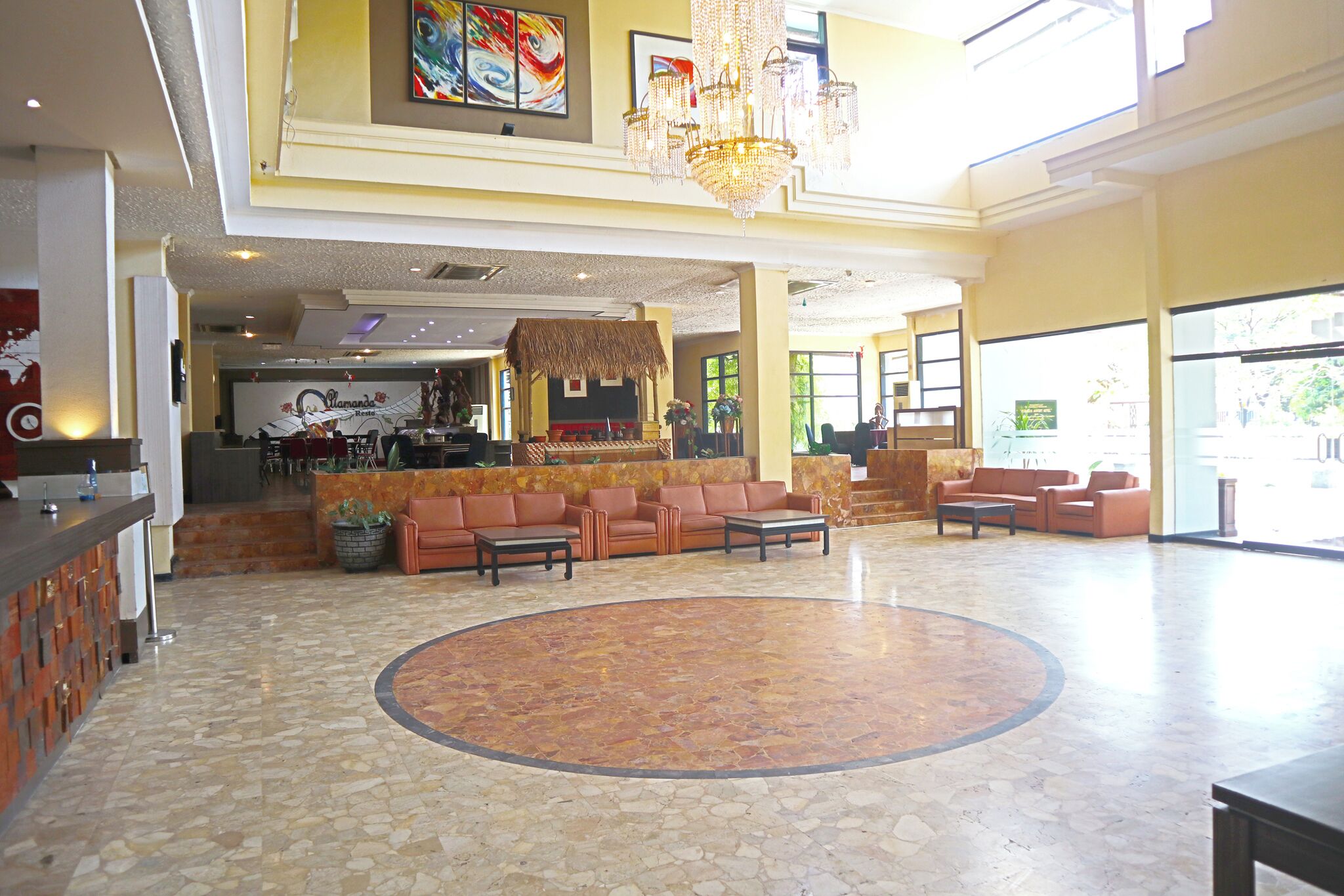 Un vestíbulo amplio con una zona de estar central, un mostrador de recepción y un bar.