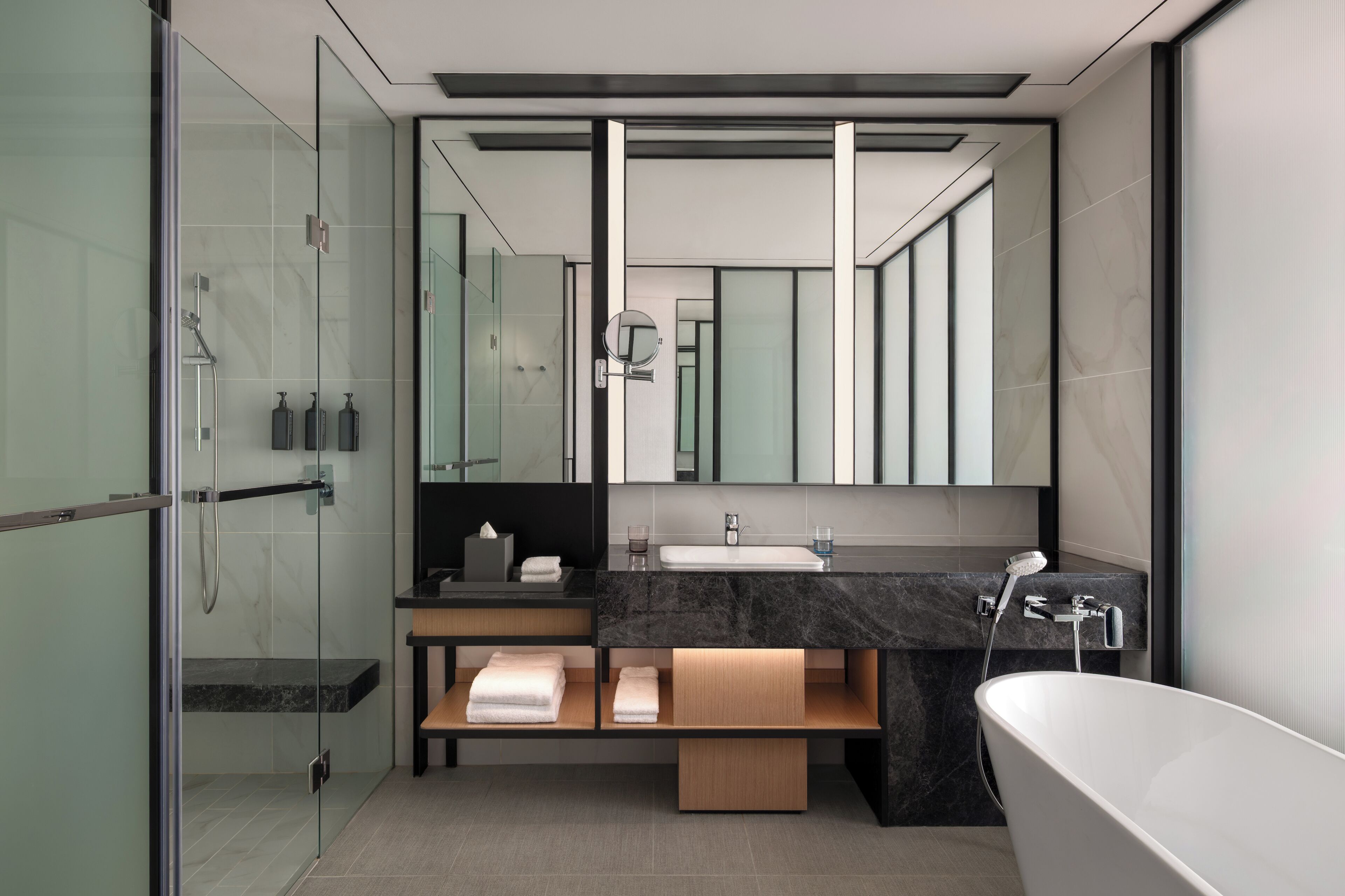 A modern bathroom with a glass-enclosed shower, a vanity with a marble countertop, and a freestanding bathtub.