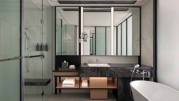A modern bathroom with a glass-enclosed shower, a vanity with a marble countertop, and a freestanding bathtub.