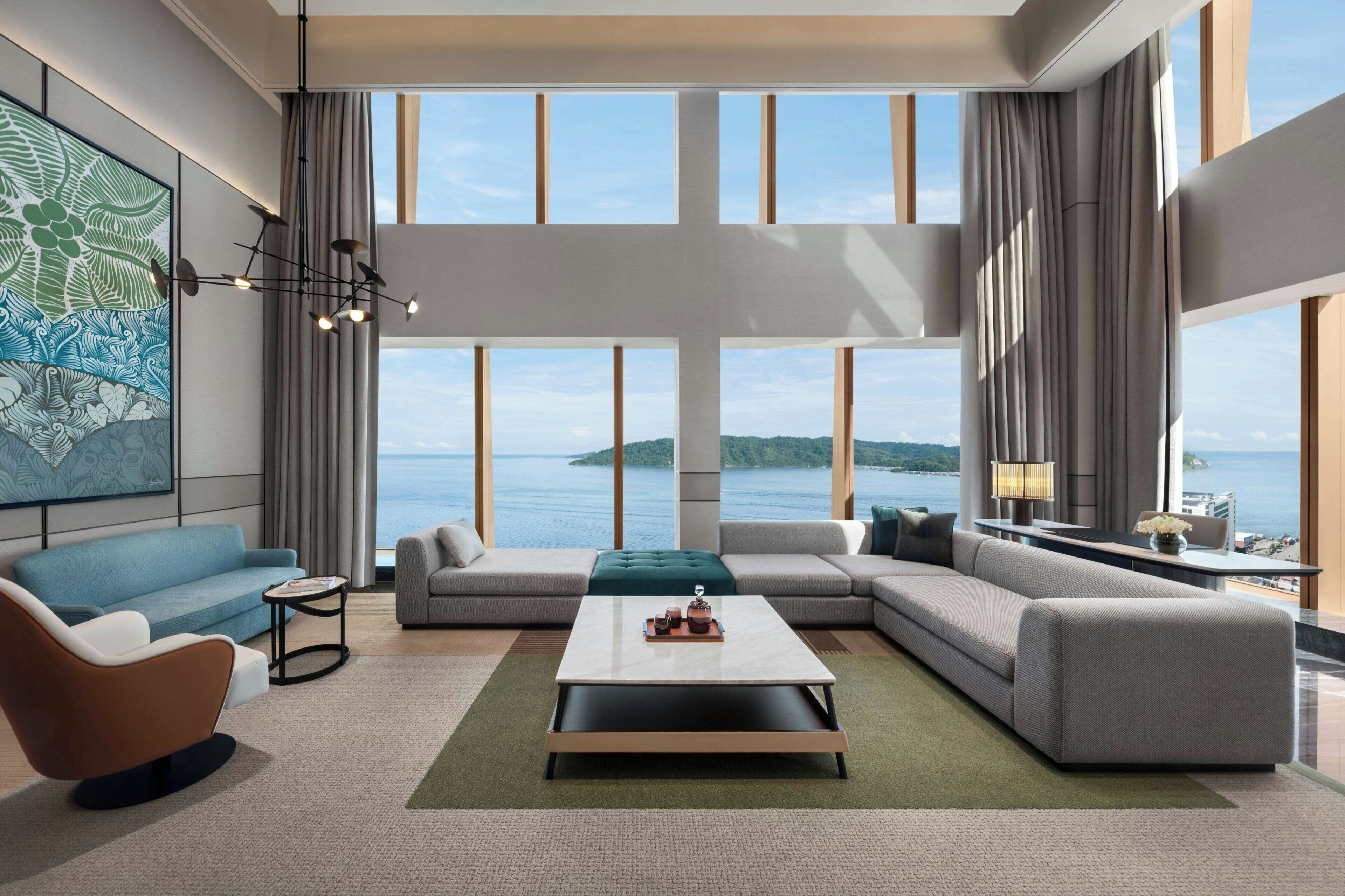 A modern living room with a large window, a sectional sofa, a coffee table, and a painting on the wall.