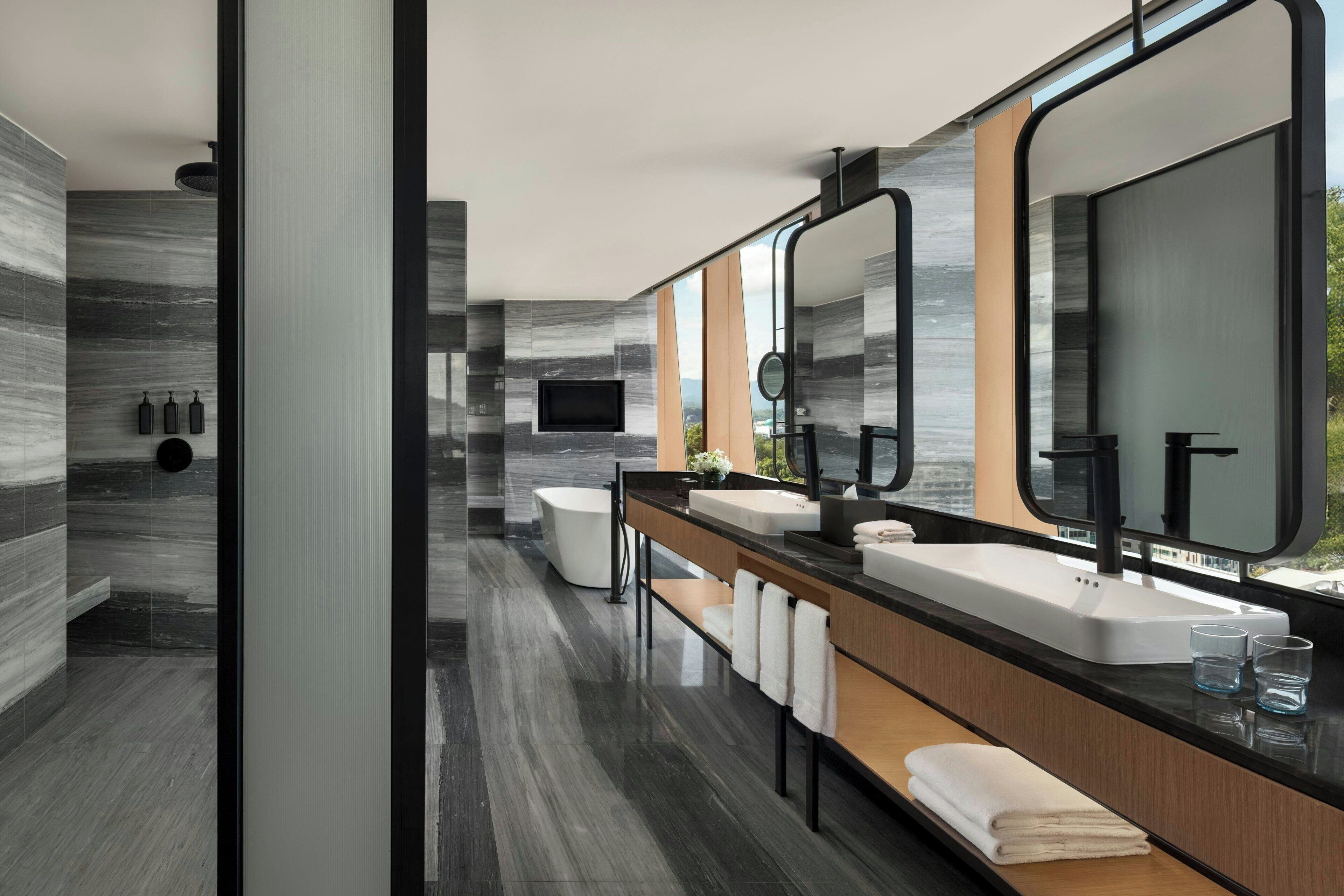 A modern bathroom with a dual sink vanity, a large mirror, and a bathtub.