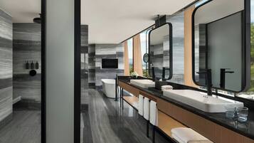 A modern bathroom with a dual sink vanity, a large mirror, and a bathtub.