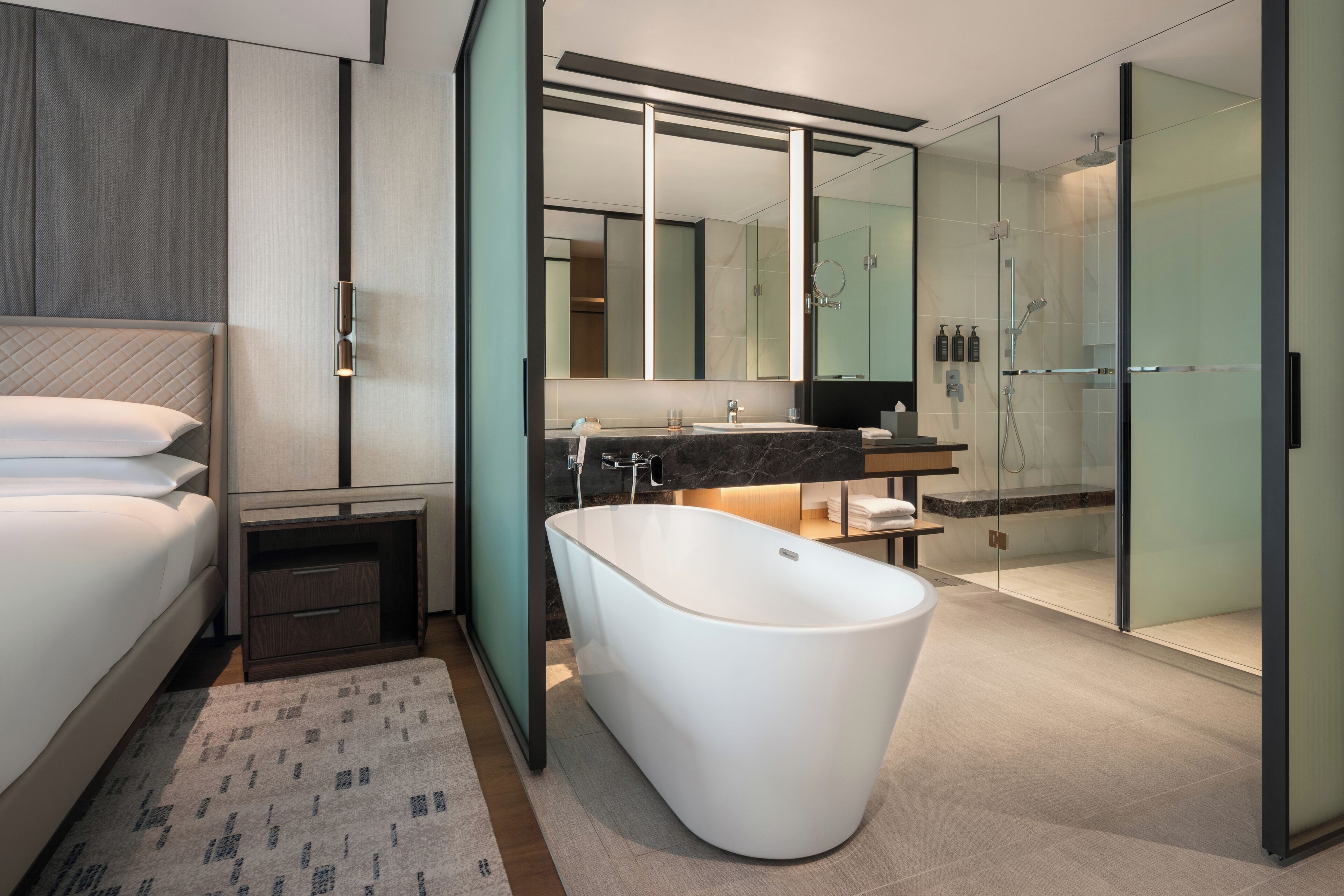 A modern bathroom with a freestanding bathtub, a large mirror, and a glass-enclosed shower area.