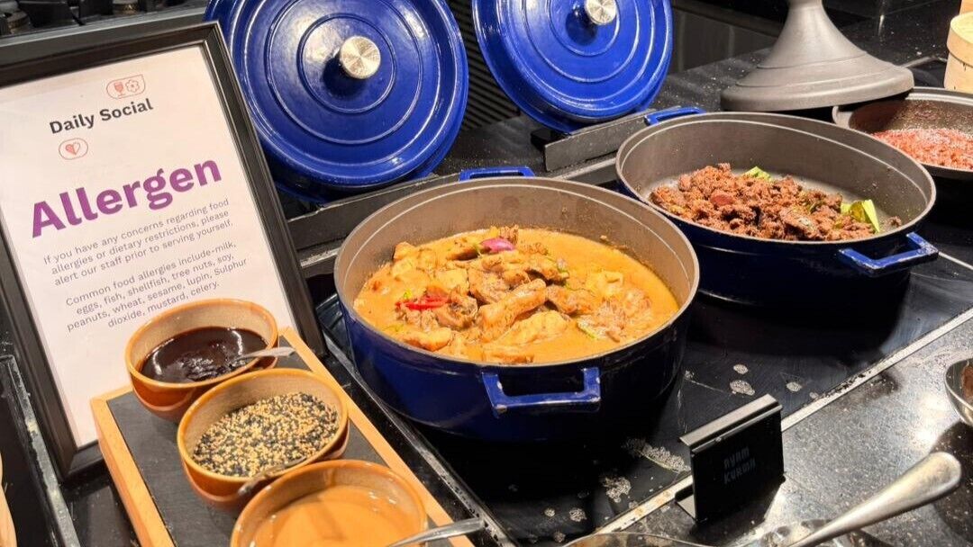 A buffet with various dishes, including a large pot of curry, a pan with minced meat, and two bowls of sauces.