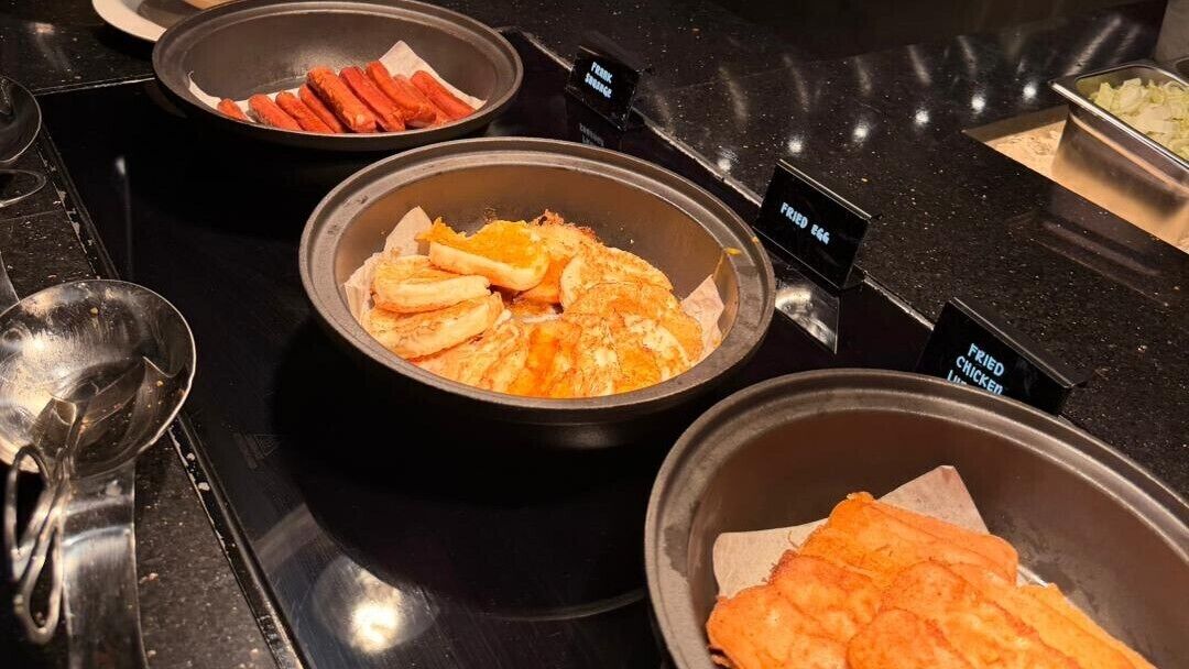 A buffet with labeled containers of fried chicken, fries, and hot dogs.