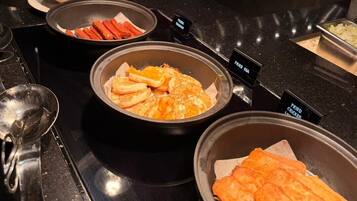 A buffet with labeled containers of fried chicken, fries, and hot dogs.