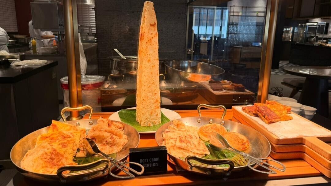 A food display with various dishes, including a tall, cylindrical item and several flatbreads.