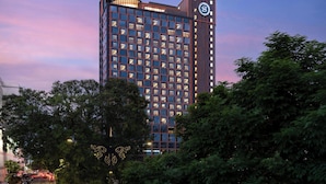 A multi-story hotel with a prominent clock tower, surrounded by trees and a busy street. - Sheraton Kota Kinabalu (Kota Kinabalu)