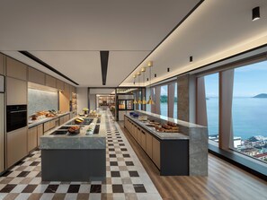 A modern kitchen with a central island, large windows, and a view of the sea. - Sheraton Kota Kinabalu (Kota Kinabalu)