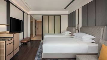 Una habitación de hotel moderna con una cama grande, un sofá, un banco, un televisor y un armario.