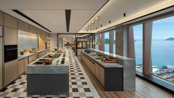 A modern kitchen with a checkered floor, a central island, and a view of the sea.