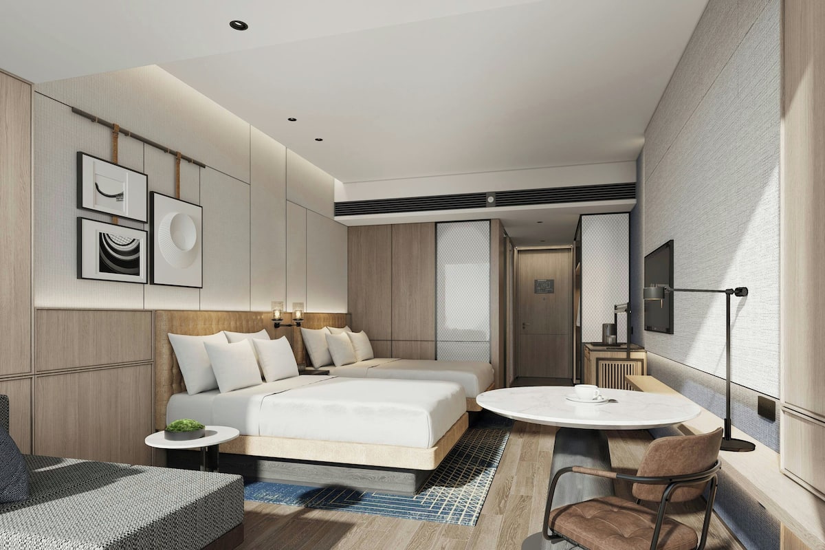 Een moderne hotelkamer met een groot bed, een ronde eettafel en een zithoek met een bank en stoelen.