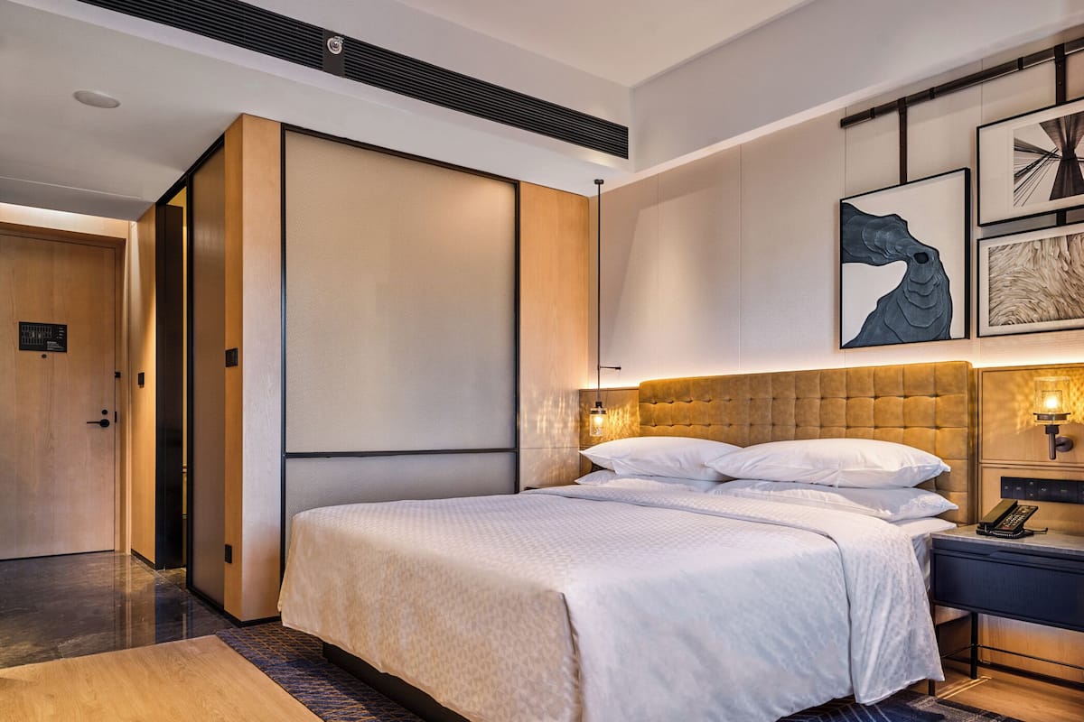Een moderne hotelkamer met een groot bed, een bureau met telefoon en kunst aan de muur.