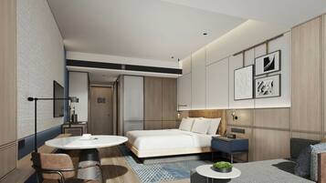 Una habitación de hotel moderna con cama, escritorio, silla, mesa redonda y sofá.