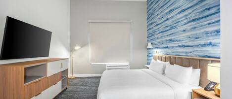 Habitación de hotel con cama, televisión, escritorio y pared con un diseño abstracto azul.