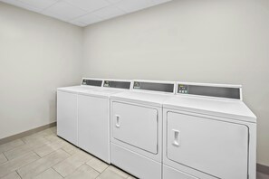 A laundry room with four white front-loading washing machines and dryers. - Towneplace Suites by Marriott Kernersville (Kernersville)