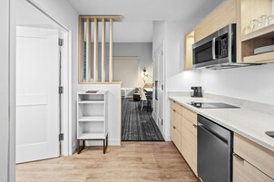 Una cucina moderna con forno a microonde integrato, lavastoviglie e un pensile in legno sopra il bancone.