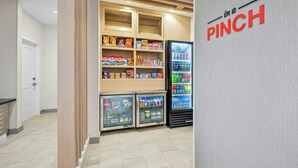 A snack and beverage vending area with multiple shelves stocked with various products and a refrigerated display case. - Towneplace Suites by Marriott Kernersville (Kernersville)