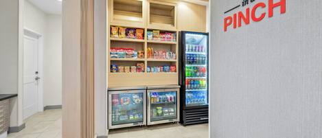 A snack and beverage vending area with multiple shelves stocked with various products and a refrigerated display case.