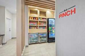 Un espace de vente proposant des collations et des boissons, avec plusieurs étagères remplies de divers produits et un présentoir réfrigéré.