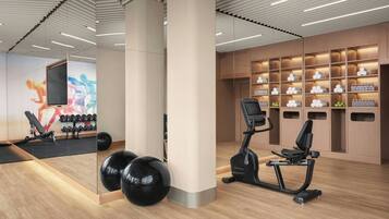 Ein modernes Fitnessstudio mit Trainingsgeräten, einer Spiegelwand und einer Wand mit ordentlich angeordneten Flaschen und Gläsern.