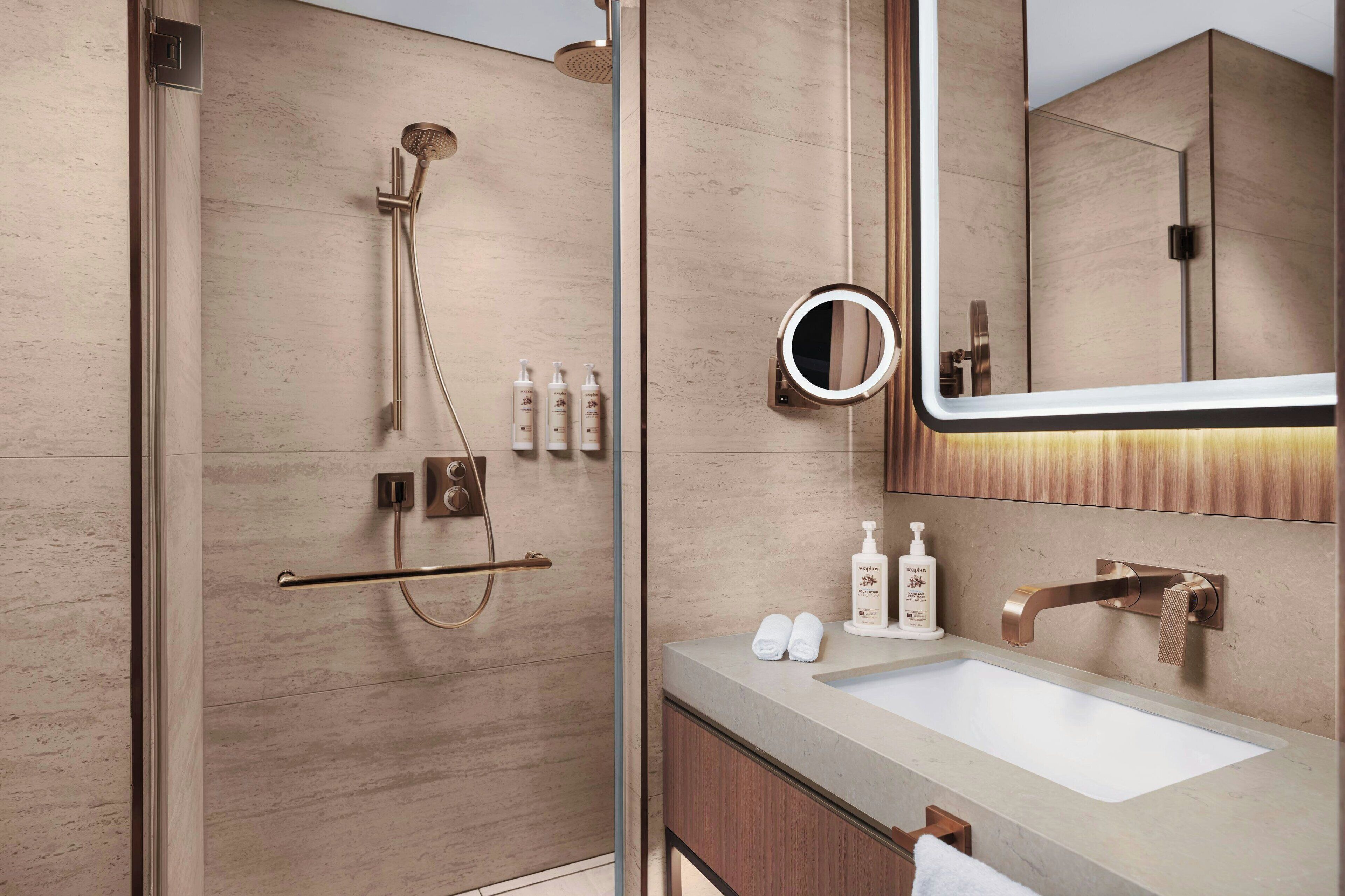 A modern bathroom with a glass-enclosed shower, a vanity with a sink, and a large mirror.