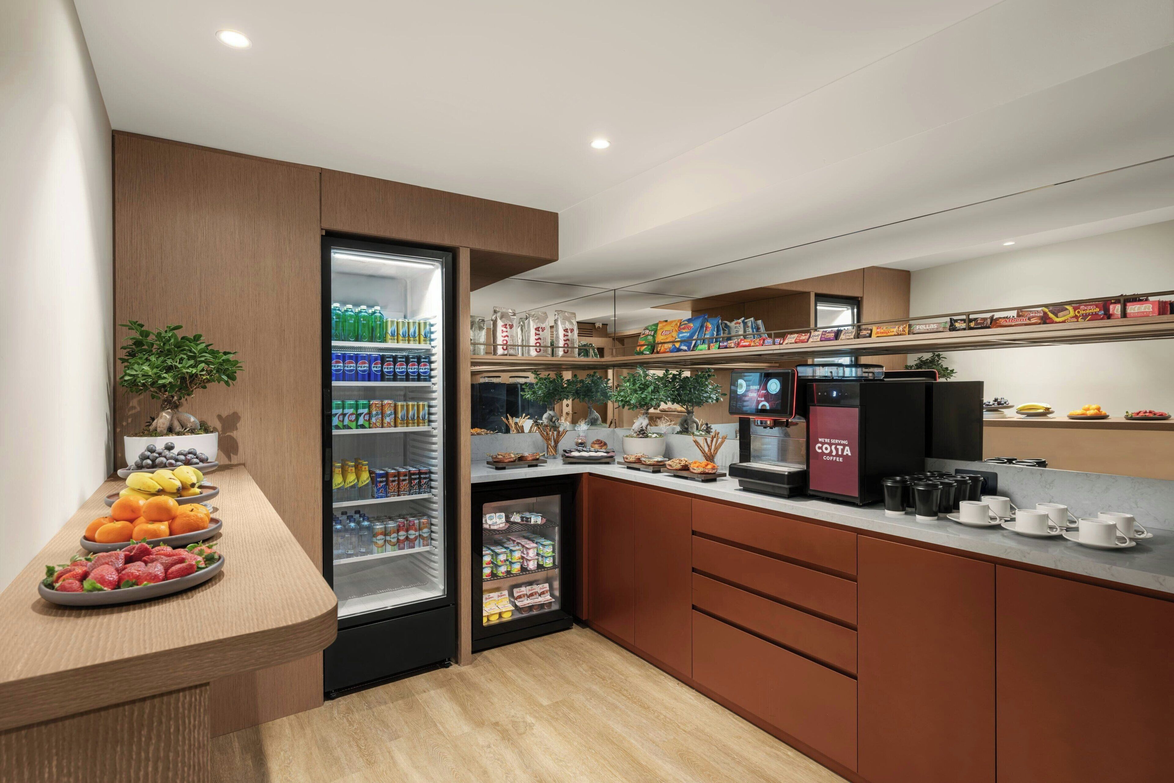 A modern kitchen with a built-in refrigerator, a coffee station, and a variety of food items displayed on shelves.