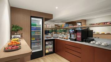 A modern kitchen with a built-in refrigerator, a coffee station, and a variety of food items displayed on shelves.