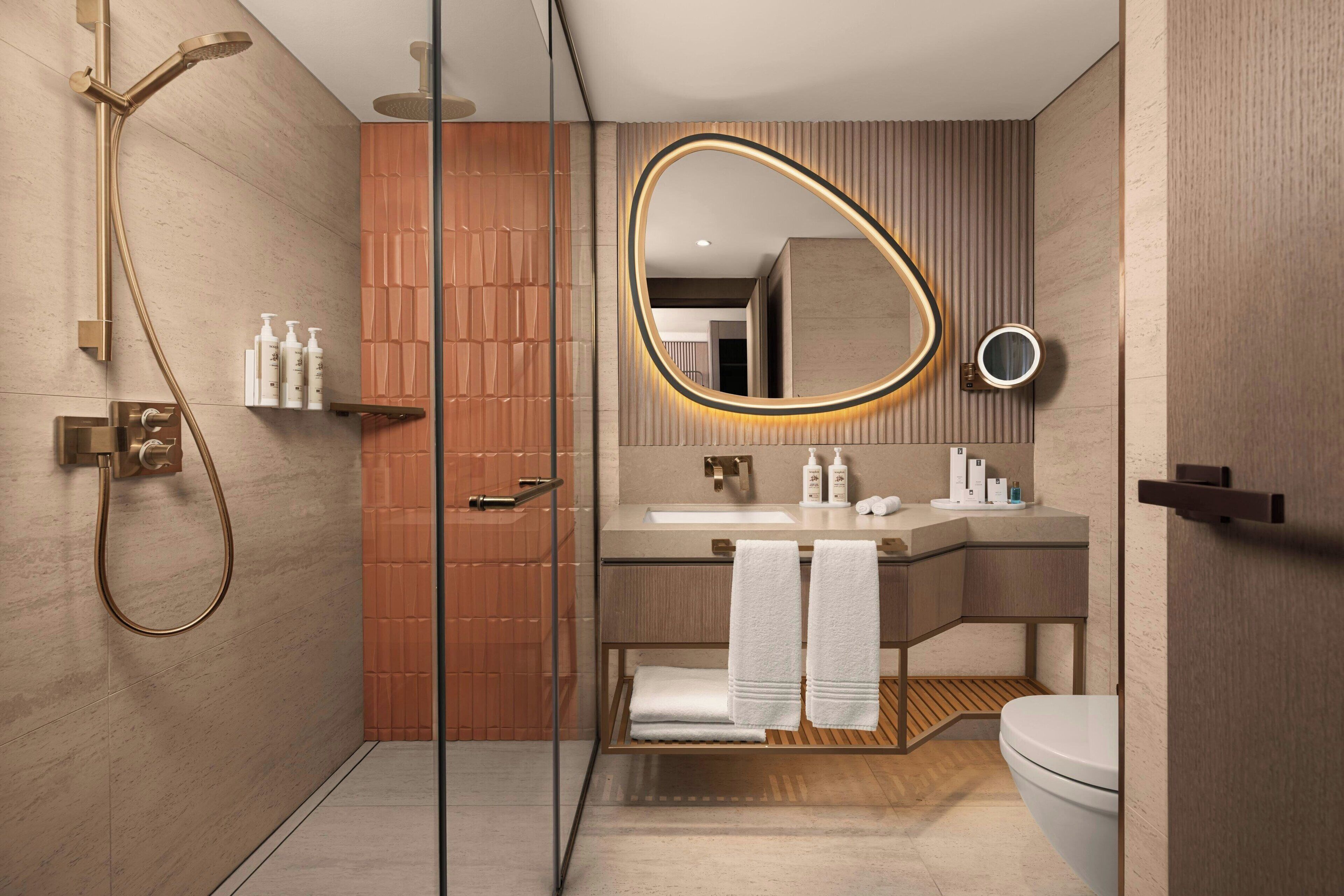 Ein modernes Badezimmer mit einer Duschkabine, einem Waschtisch mit Spiegel und einer Toilette.