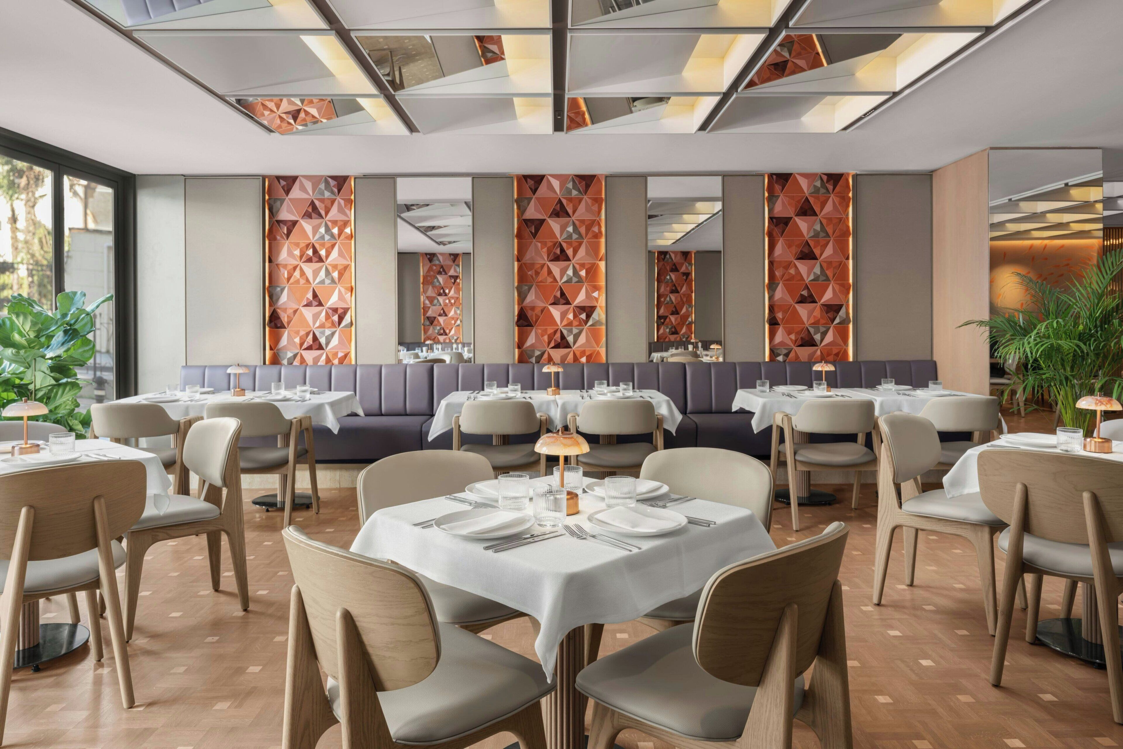 A restaurant with round tables, cushioned booths, and geometric wall patterns.