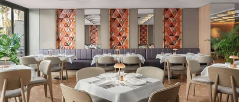 A restaurant with round tables, cushioned booths, and geometric wall patterns.