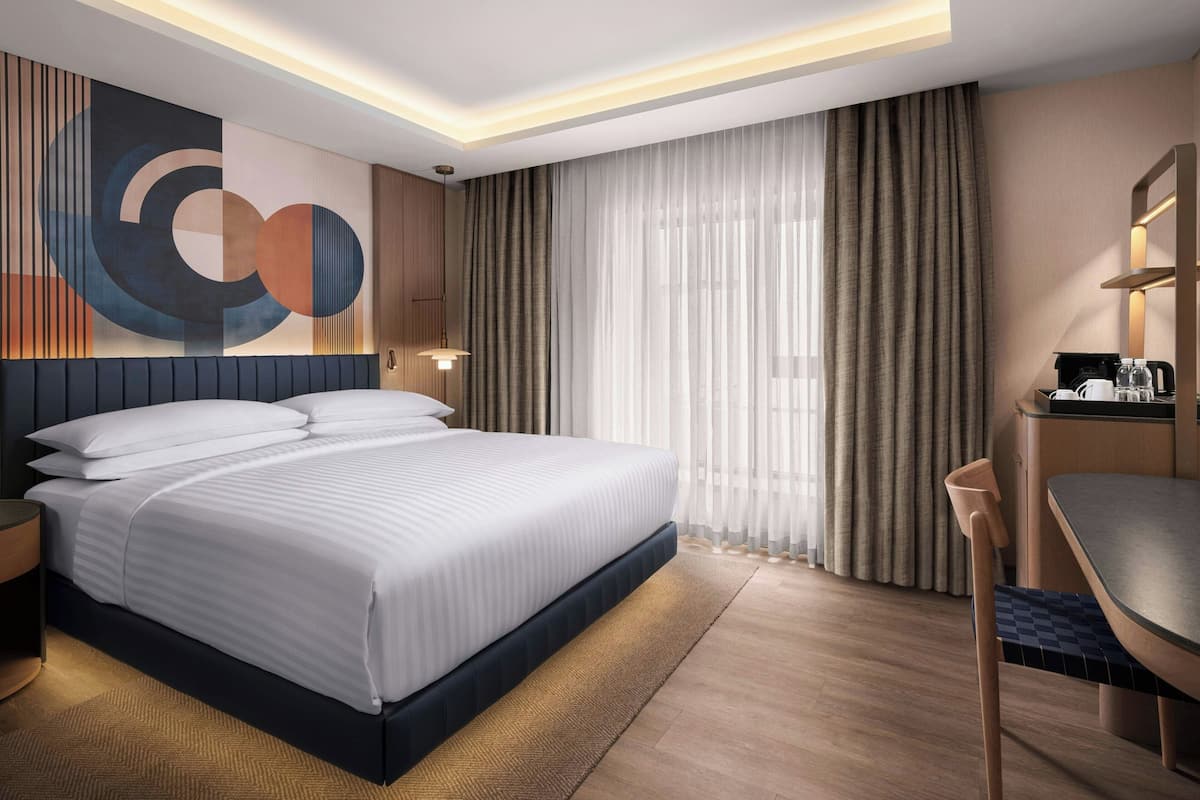 A modern hotel room with a large bed, a desk, and a wall-mounted TV.