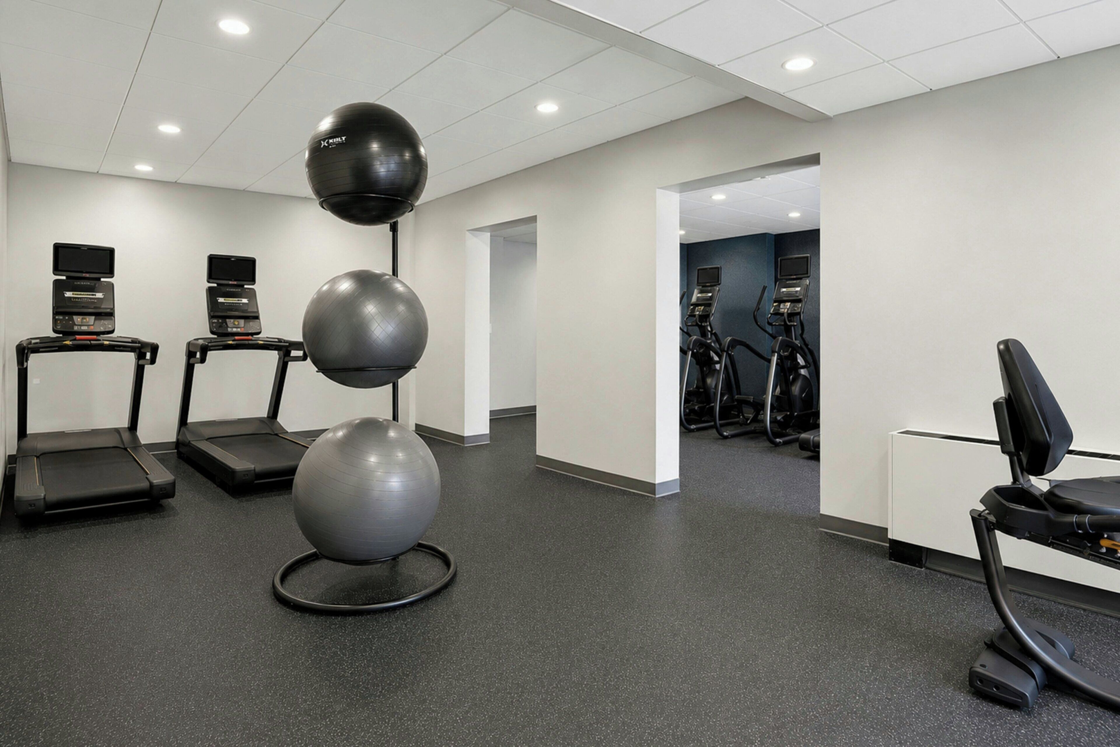 A fitness room with treadmills, exercise balls, and stationary bikes.