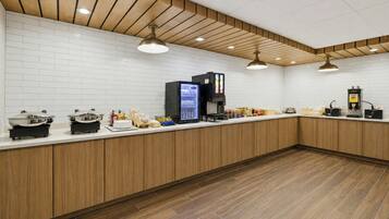 Un espace cuisine moderne avec un dosseret de carrelage blanc, des armoires en bois et un plan de travail agrémenté de divers appareils et condiments.
