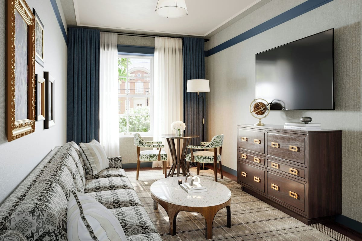 Een moderne hotelkamer met een bank, een rond bijzettafeltje, een televisie en een dressoir.