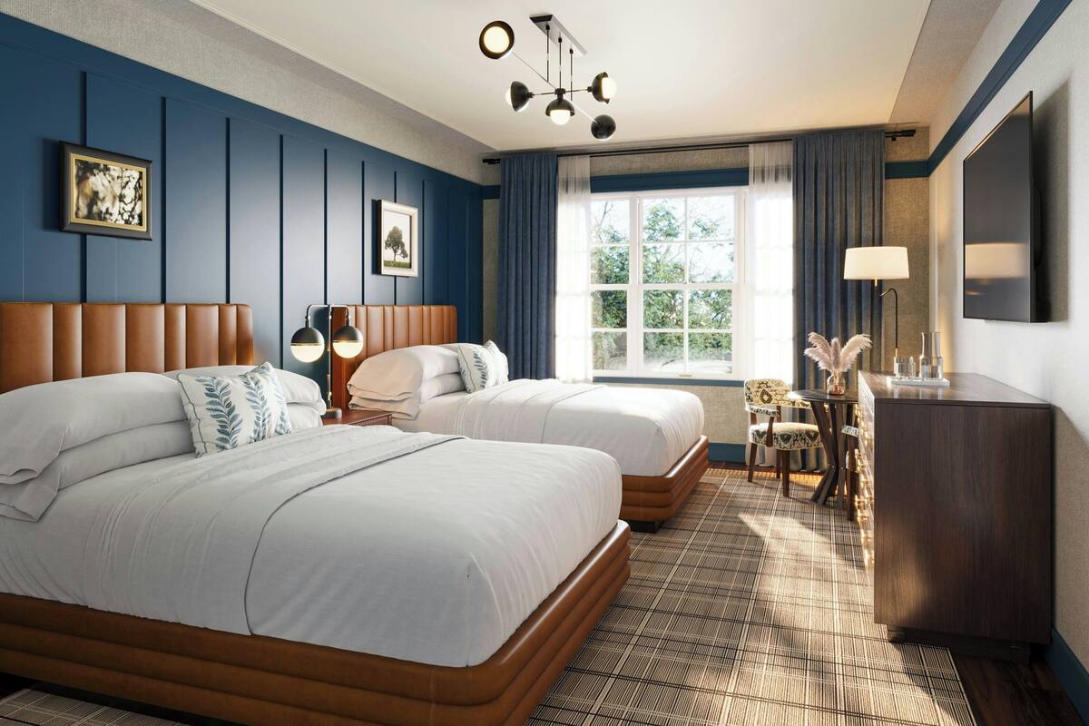 Een hotelkamer met twee bedden, een bureau, een stoel, een televisie en een raam met gordijnen.