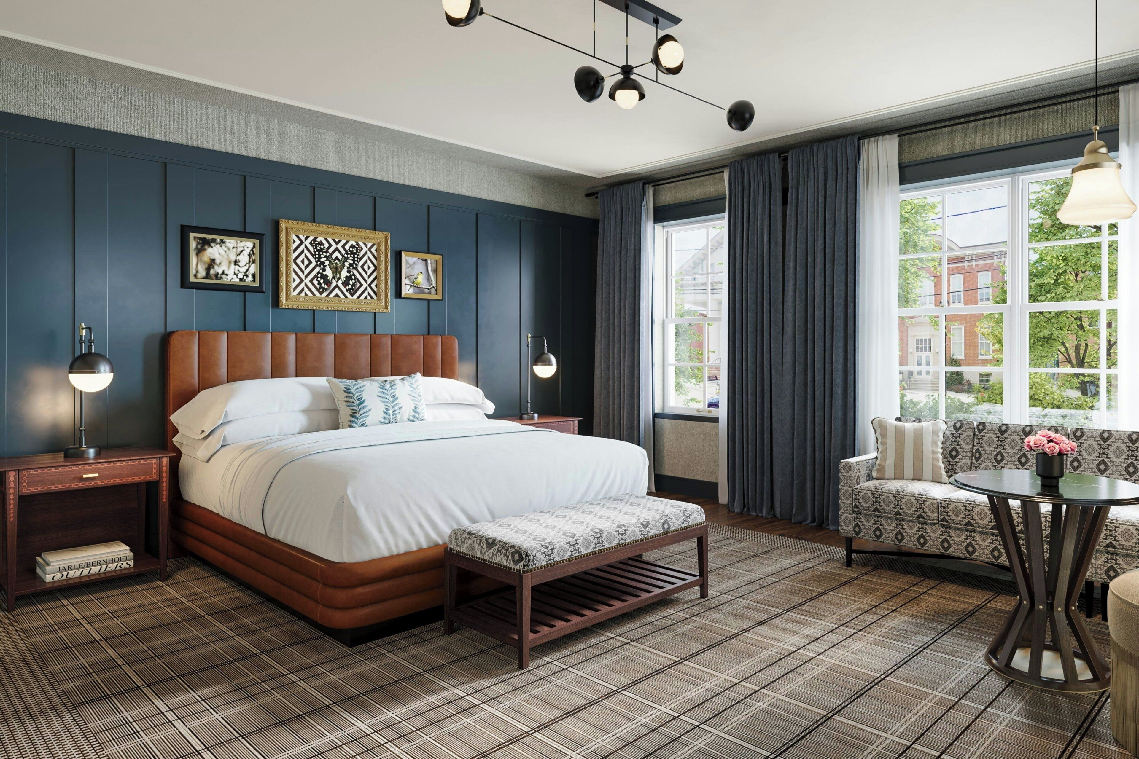 A modern hotel room with a large bed, a bench, a sofa, and a table.