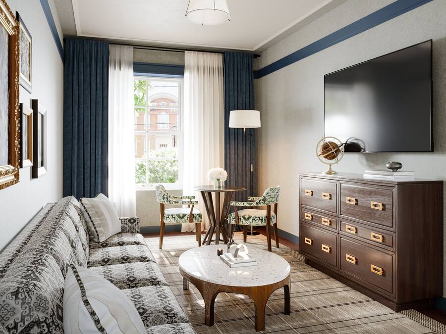 Ein Hotelzimmer mit einer Couch, einem Couchtisch, einem Fernseher, einem Schminktisch und einem Fenster mit Vorhängen.