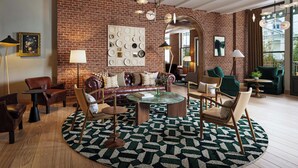 A spacious living room with a brick wall, leather sofa, round coffee table, and modern lighting fixtures. - The Union Hotel, Flemington, A Tribute Portfolio Hotel (Flemington)
